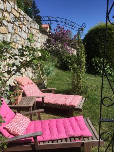 un groupe de bancs avec des coussins roses dans une cour dans l'établissement Rez de jardin de chalet bois , calme et verdure !, à Saint-Martin-Vésubie