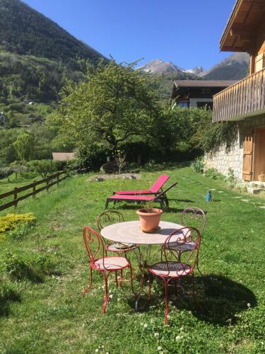 a table with four chairs and a pot on it at Rez de jardin de chalet bois , calme et verdure ! in Saint-Martin-Vésubie