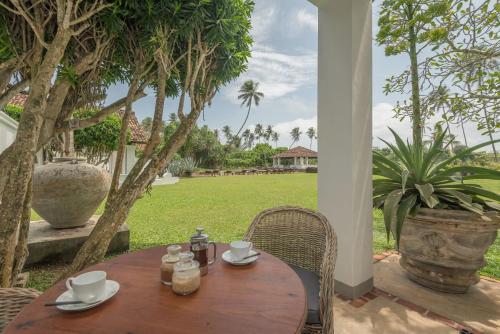 a wooden table and chairs on a patio at The Villa Bentota by KK Collection in Bentota