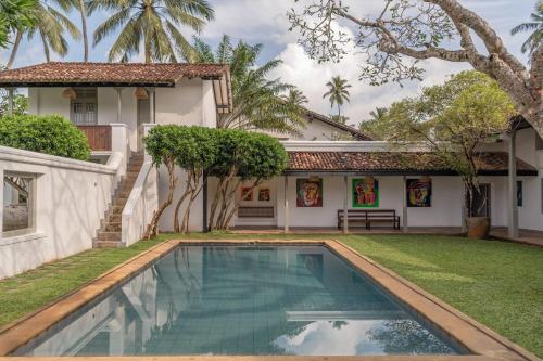 a swimming pool in front of a house at The Villa Bentota by KK Collection in Bentota