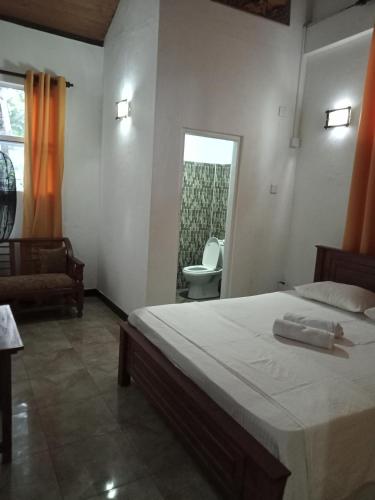 a bedroom with a bed and a chair and a window at Leopard Rock Family Rest in Katunayake
