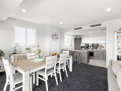 a kitchen and dining room with a wooden table and chairs at Cove 401 in Forster