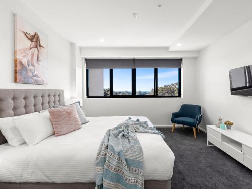 a bedroom with a large bed and a blue chair at Cove 401 in Forster