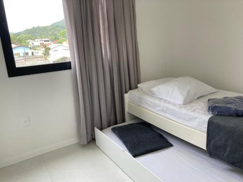 - un petit lit dans une chambre avec fenêtre dans l'établissement Conchas de Palmas, à Governador Celso Ramos