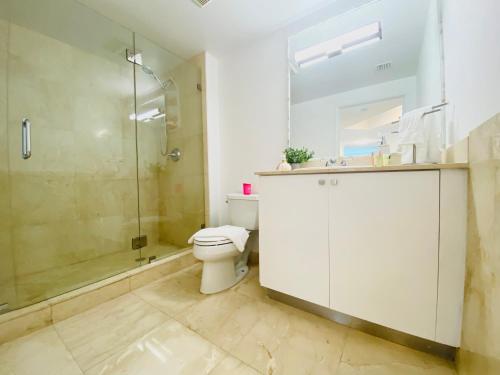 a bathroom with a toilet and a glass shower at The King David Condos in Miami Beach