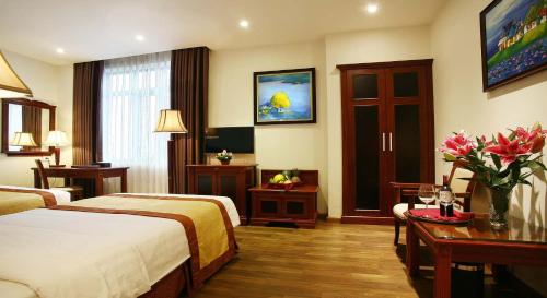 a hotel room with two beds and a table with flowers at Western Hanoi Hotel in Hanoi