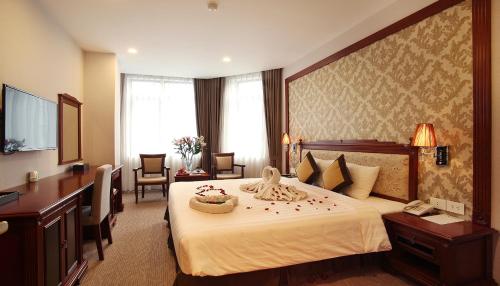 a hotel room with a large bed with flowers on it at Western Hanoi Hotel in Hanoi