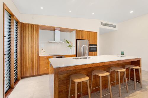 a kitchen with wooden cabinets and a counter with bar stools at Azure at Funnel Bay in Airlie Beach