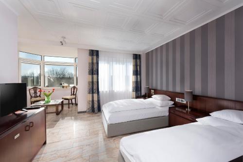 a hotel room with two beds and a television at Hotel Harheimer Hof in Frankfurt/Main
