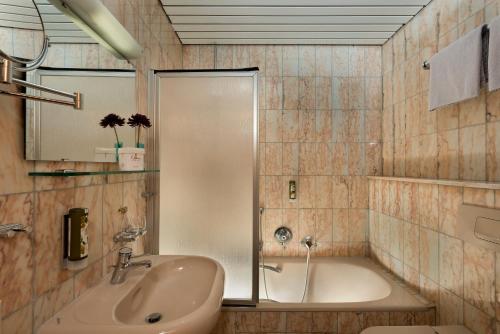 a bathroom with a sink and a bath tub at Hotel Harheimer Hof in Frankfurt