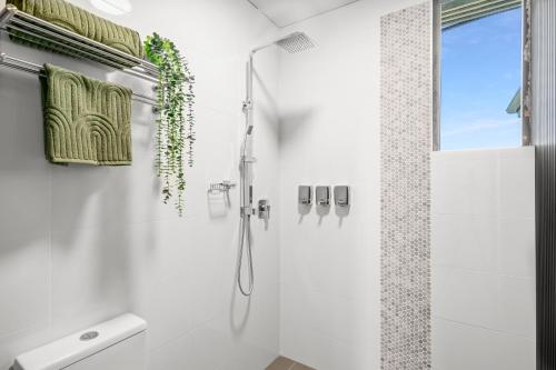 a white bathroom with a shower and a sink at Grand Hotel and Studios in Wyong