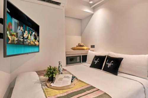 a living room with a white couch and a tv at lyf one-north Singapore in Singapore