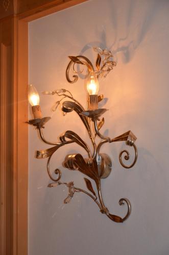a bronze chandelier with lights on a wall at Garni Franca b&b in Selva di Val Gardena