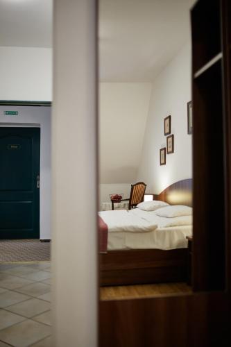 a bedroom with a bed and a chair in a room at Tercia Hubertus Panzió in Sopron