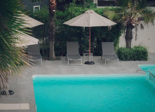 two chairs and an umbrella next to a swimming pool at Chanalai Resort and Hotel in Ban Pa Yang
