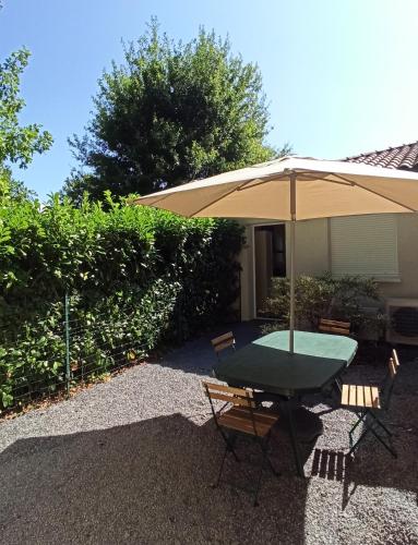 une table avec un parasol et deux chaises dans l'établissement T1 cosy climatisé indépendant sur prop privée à Sanguinet - lac, océan, Bassin d'Arcachon, Dune du Pyla, à Sanguinet