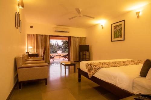 a bedroom with a bed and a couch and a chair at Amritara Ambatty Greens Resort in Virajpet