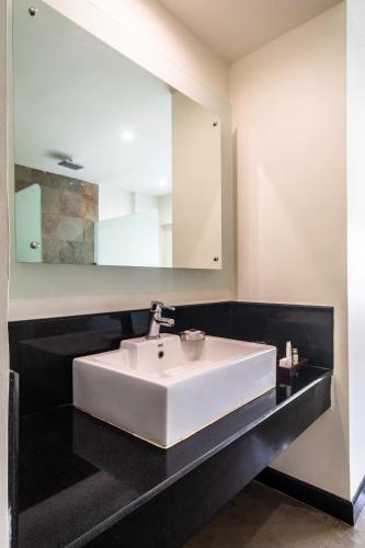 a bathroom with a white sink and a mirror at Amritara Ambatty Greens Resort in Virajpet