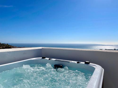 una bañera con el océano en el fondo en Bayview -Superb Luxurious Sea View Penthouse with private hot tub by Solrentspain en Benalmádena