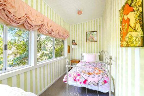 a bedroom with a bed and two windows at Cherry Tree Cottage in Leura