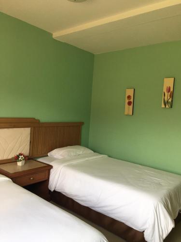 two beds in a room with green walls at Samerdrow Khao Yai in Mu Si
