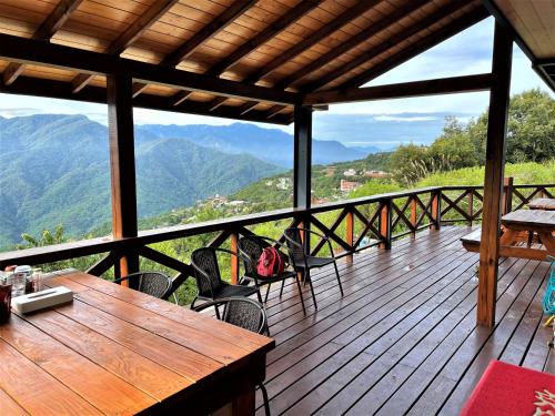 a wooden deck with a table and chairs and mountains at Shiyai Taoyuan in Renai