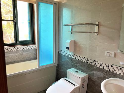 a bathroom with a toilet and a sink and a window at Shiyai Taoyuan in Renai