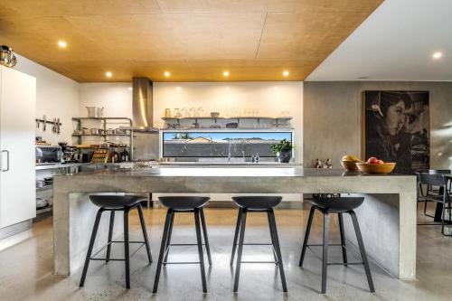 a large kitchen with a large concrete island with bar stools at Waves - Lennox Head in Lennox Head