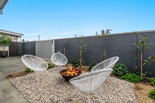 three white chairs and a fire pit in a yard at Waves - Lennox Head in Lennox Head
