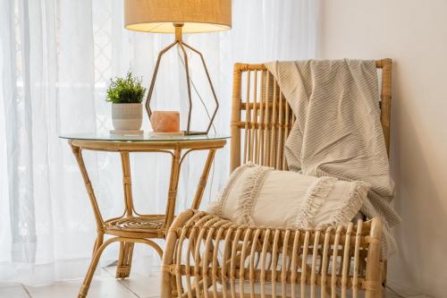 a rattan chair and a table with a lamp at Wintersview 9 - Lennox Head in Lennox Head