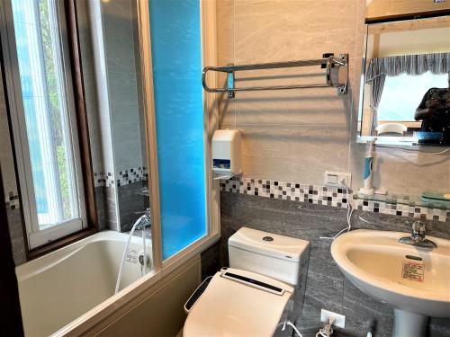 a bathroom with a toilet and a sink and a tub at Shiyai Taoyuan in Renai