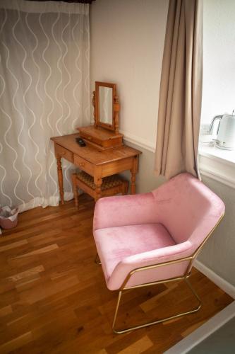 a pink chair sitting next to a table with a mirror at The Chagford Inn in Chagford