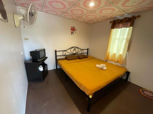 a bedroom with a yellow bed and a tv at ภูน้ำทิพย์ รีสอร์ท in Ban Huai Phai