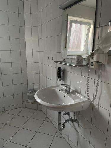 a white bathroom with a sink and a phone at Lippborger-Hof in Lippetal