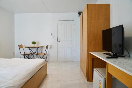 a bedroom with a bed and a table with a television at View Place Hotel & Residence in Bangkok
