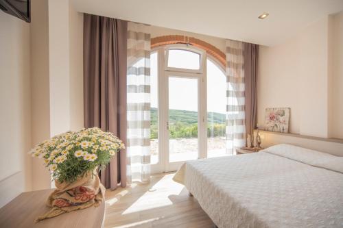 Un dormitorio con una cama y una ventana con un jarrón de flores en Agriturismo Casa Zen, en San Martino Buon Albergo