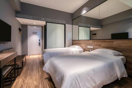 a bedroom with two beds and a flat screen tv at 有集城市客栈锦绣中华店Unijoy Cityinn Splendid China Shenzhen in Shenzhen
