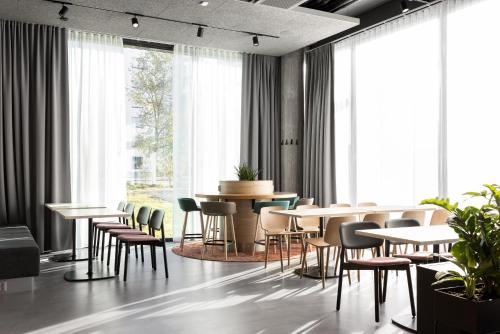 a dining room with tables and chairs and windows at Noli Myyrmäki in Vantaa