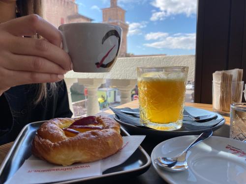 a person drinking a cup of coffee with a doughnut and orange juice at Letto A Castello in Ferrara