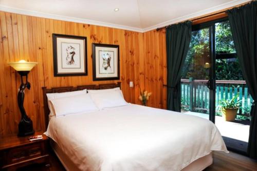 Un dormitorio con una cama blanca y una ventana. en Clouds Chalet, en Beechmont