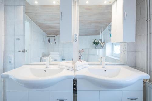 two sinks in a bathroom with white tiles at Sputnik in Nordstrand