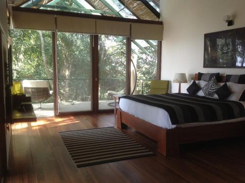 a bedroom with a bed and large glass windows at Waterwoods Lodge Kabini in Begūr