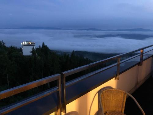 a balcony with a chair and a view of the clouds at Apartman Panorama 805 in Štrbské Pleso