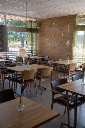 a dining room with tables and chairs and a clock at Nätra Motell in Bjästa