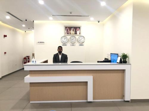 a man sitting at a counter in a lobby at JOOD RESIDENCE in Seef