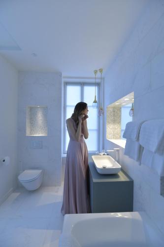 a woman standing in a bathroom talking on a cell phone at CHATEAU DE BRINVILLE in Saint-Sauveur-sur-École