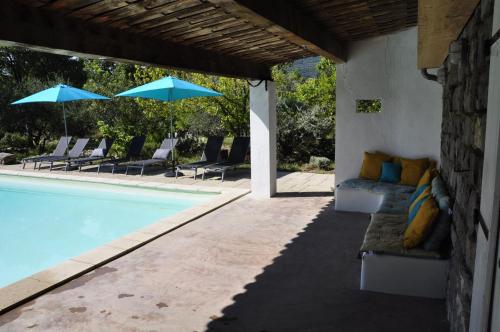 a swimming pool with lounge chairs and umbrellas next to a swimming pool at Un je ne sais quoi de Paradis in Les Vans
