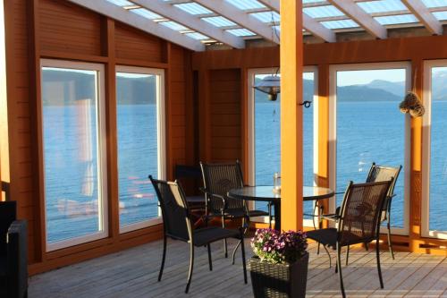 a dining room with a table and chairs and the ocean at Hjelvikhytta - flott beliggenhet ved sjøen in Hjelvik