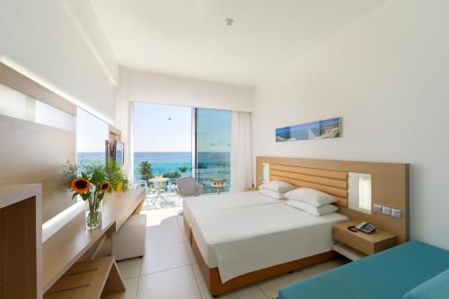 a bedroom with a bed and a large window at Vrissaki Beach Hotel in Protaras