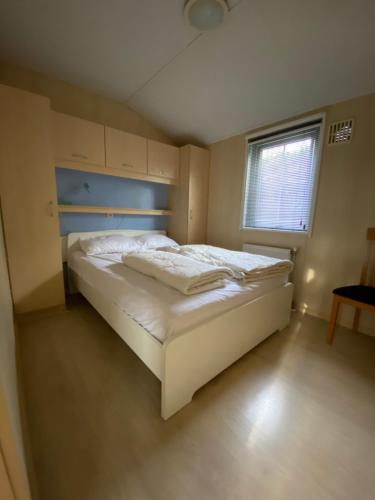 a small bedroom with a white bed with a window at Chalet Togo in Wageningen